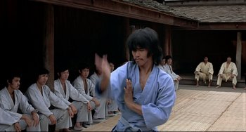 Movie still from “The Man with the Golden Gun” (1974), directed by Guy Hamilton – A man in a blue robe is performing a martial arts move; Medium shot, Over the shoulder angle