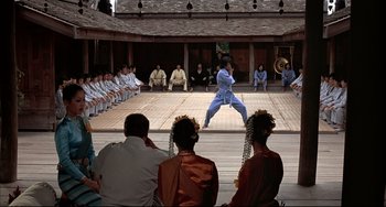 A man in a blue robe is performing a martial arts move