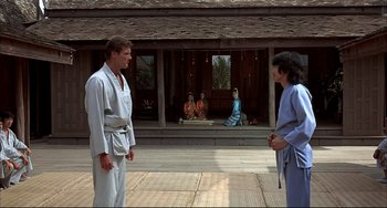 Movie still from “The Man with the Golden Gun” (1974), directed by Guy Hamilton – A man and a woman are standing in front of a building; Wide shot, Over the shoulder angle