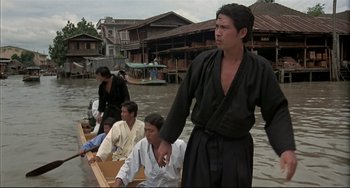 Movie still from “The Man with the Golden Gun” (1974), directed by Guy Hamilton – A group of people in a boat on a body of water; Wide shot, Low angle