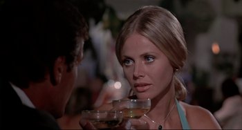 Movie still from “The Man with the Golden Gun” (1974), directed by Guy Hamilton – A woman holding a glass of wine in front of a man; Close Up shot, Over the shoulder angle