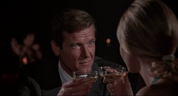Movie still from “The Man with the Golden Gun” (1974), directed by Guy Hamilton – A man and a woman drinking wine at a party; Close Up shot, Over the shoulder angle
