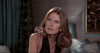 Movie still from “The Man with the Golden Gun” (1974), directed by Guy Hamilton – A beautiful woman with long brown hair wearing a black dress; Close Up shot, Low angle