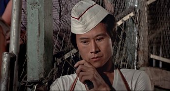 Movie still from “The Man with the Golden Gun” (1974), directed by Guy Hamilton – A man wearing a white hat is talking on a cell phone; Close Up shot, Low angle