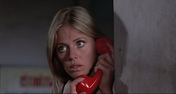 Movie still from “The Man with the Golden Gun” (1974), directed by Guy Hamilton – A woman holding a red phone up to her ear; Close Up shot, Low angle