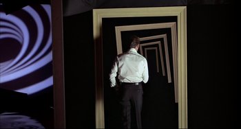 Movie still from “The Man with the Golden Gun” (1974), directed by Guy Hamilton – A man standing in front of an open door; Wide shot, High angle