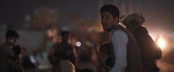 Movie still from “Retrograde” (2022), directed by Matthew Heineman – A man holding a baby in his arms at night; Close Up shot, Over the shoulder angle