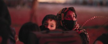 Movie still from “Retrograde” (2022), directed by Matthew Heineman – A woman and a child are sitting on a couch; Extreme Close Up shot, Low angle