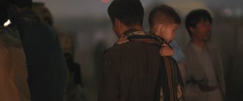 Movie still from “Retrograde” (2022), directed by Matthew Heineman – A man holding a baby in his arms; Close Up shot, Over the shoulder angle