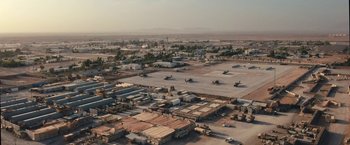 Movie still from “Retrograde” (2022), directed by Matthew Heineman – An aerial view of an industrial area in the middle of the desert; Extreme Wide shot, High angle