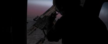 Movie still from “Retrograde” (2022), directed by Matthew Heineman – A man in a black shirt holding a gun; Wide shot, High angle