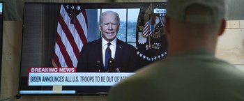 Movie still from “Retrograde” (2022), directed by Matthew Heineman – A man watching a tv screen with a picture of joe biden on it; Extreme Close Up shot, Over the shoulder angle