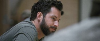 Movie still from “Retrograde” (2022), directed by Matthew Heineman – A man with a goatee and a beard looking to his left; Close Up shot, Over the shoulder angle