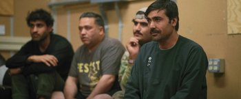 Movie still from “Retrograde” (2022), directed by Matthew Heineman – A group of men sitting next to each other in a room; Close Up shot, Over the shoulder angle