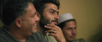 Movie still from “Retrograde” (2022), directed by Matthew Heineman – A man with a beard is looking at the camera; Close Up shot, Over the shoulder angle