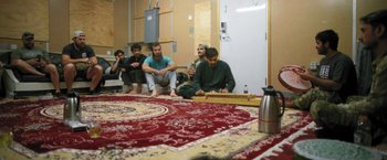 Movie still from “Retrograde” (2022), directed by Matthew Heineman – A group of men sitting on the floor of a room; Wide shot, High angle