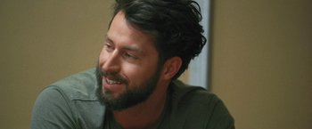 Movie still from “Retrograde” (2022), directed by Matthew Heineman – A man with a beard smiling at the camera; Close Up shot, Over the shoulder angle