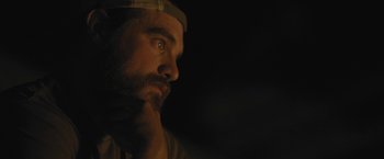 Movie still from “Retrograde” (2022), directed by Matthew Heineman – A man with a beard is looking into the distance; Close Up shot, Over the shoulder angle