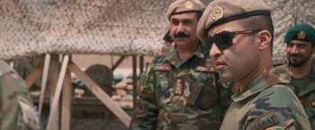 Movie still from “Retrograde” (2022), directed by Matthew Heineman – A couple of men standing next to each other; Close Up shot, Over the shoulder angle