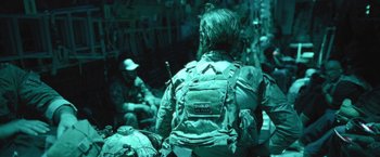 Movie still from “Retrograde” (2022), directed by Matthew Heineman – A man with a beard wearing a back pack; Medium shot, Over the shoulder angle