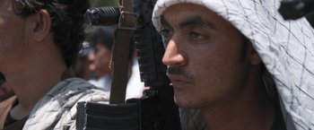 Movie still from “Retrograde” (2022), directed by Matthew Heineman – A person holding a gun; Close Up shot, Low angle