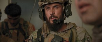 Movie still from “Retrograde” (2022), directed by Matthew Heineman – A man with a beard wearing a helmet; Close Up shot, Over the shoulder angle