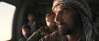 Movie still from “Retrograde” (2022), directed by Matthew Heineman – A person with a beard wearing a headscarf; Close Up shot, Over the shoulder angle