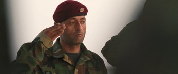 Movie still from “Retrograde” (2022), directed by Matthew Heineman – A soldier saluting while wearing a maroon hat; Close Up shot, Low angle