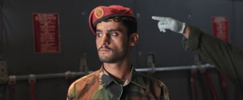 Movie still from “Retrograde” (2022), directed by Matthew Heineman – A man in a military uniform wearing a red hat; Close Up shot, Low angle