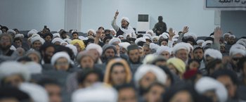 Movie still from “Retrograde” (2022), directed by Matthew Heineman – A large group of people in a large room; Wide shot, High angle