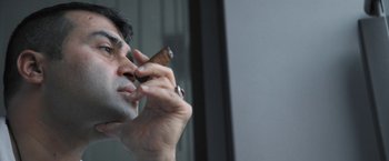 Movie still from “Retrograde” (2022), directed by Matthew Heineman – A person holding a cigar; Close Up shot, Low angle