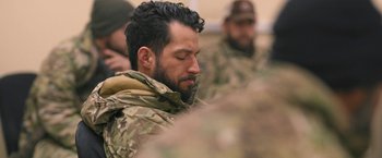 Movie still from “Retrograde” (2022), directed by Matthew Heineman – A person with a beard; Close Up shot, Over the shoulder angle