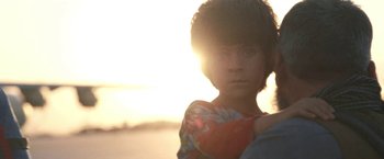 Movie still from “Retrograde” (2022), directed by Matthew Heineman – A young girl is standing in front of the setting sun; Extreme Close Up shot, Low angle