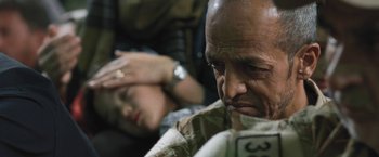 Movie still from “Retrograde” (2022), directed by Matthew Heineman – A man and a woman sitting next to each other on the ground; Close Up shot, Over the shoulder angle