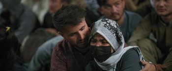 Movie still from “Retrograde” (2022), directed by Matthew Heineman – A man and a woman wearing a face mask; Extreme Close Up shot, High angle