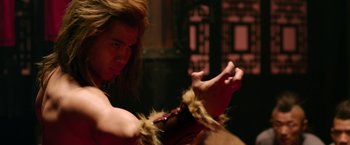 Movie still from “The Man with the Iron Fists” (2012), directed by RZA – A man with long brown hair is holding something in his hands; Close Up shot, Over the shoulder angle