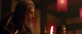 Movie still from “The Man with the Iron Fists” (2012), directed by RZA – A person with long hair is looking at a candle; Close Up shot, Over the shoulder angle