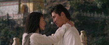 Movie still from “The Man with the Iron Fists” (2012), directed by RZA – A man and a woman embracing each other in front of trees; Close Up shot, Low angle