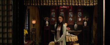 Movie still from “The Man with the Iron Fists” (2012), directed by RZA – A woman standing in front of a table with vases; Medium shot, Low angle