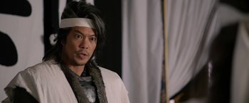 Movie still from “The Man with the Iron Fists” (2012), directed by RZA – A man with a bandage on his head; Close Up shot, Over the shoulder angle