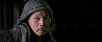 Movie still from “The Man with the Iron Fists” (2012), directed by RZA – An older man wearing a hat and a scarf; Close Up shot, Low angle