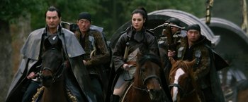 Movie still from “The Man with the Iron Fists” (2012), directed by RZA – A group of people riding horses on a field; Medium shot, Over the shoulder angle
