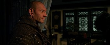 Movie still from “The Man with the Iron Fists” (2012), directed by RZA – A man with a bald head wearing a scarf looking to his left; Close Up shot, Over the shoulder angle