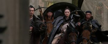 Movie still from “The Man with the Iron Fists” (2012), directed by RZA – A group of people riding horses on a city street; Medium shot, Low angle