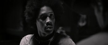 Movie still from “The Man with the Iron Fists” (2012), directed by RZA – A black and white photo of a man with a afro looking into the distance; Close Up shot, Low angle