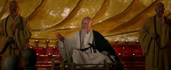 Movie still from “The Man with the Iron Fists” (2012), directed by RZA – An old man sitting in a chair wearing a robe; Medium shot, Low angle