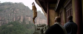 Movie still from “The Man with the Iron Fists” (2012), directed by RZA – A man is doing a handstand on a railing; Wide shot, Low angle