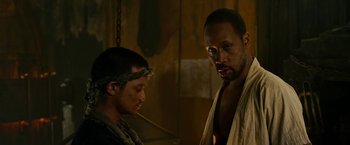 Movie still from “The Man with the Iron Fists” (2012), directed by RZA – Two men standing next to each other in a dimly - lit room; Close Up shot, Low angle