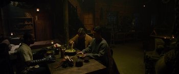 Movie still from “The Man with the Iron Fists” (2012), directed by RZA – Two men sitting at a wooden table in a dark room; Medium shot, High angle
