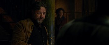Movie still from “The Man with the Iron Fists” (2012), directed by RZA – A man standing next to a pole in a dark room; Medium shot, Over the shoulder angle